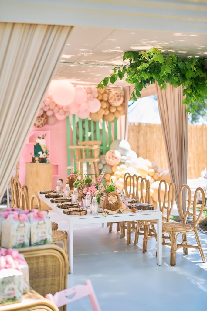 Safari-themed birthday table under a pavilion with balloon arch
